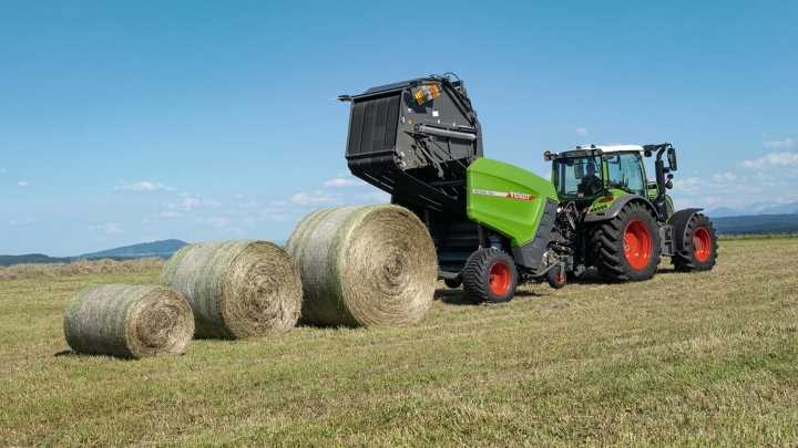 Rolnik prowadzi ciągnik Fendt Rotana 160V Xtra po polu, a za nim leżą trzy bele siana.