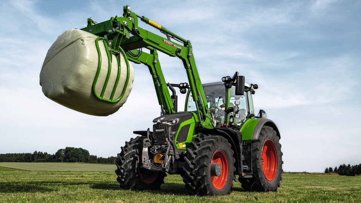 En Fendt 600 Vario med frontlastare står på en åker med en silobal.