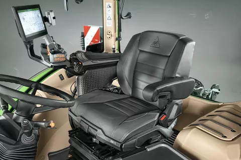 Interior photo of the cab of a Fendt 700 Vario Gen7 with the seat, passenger seat, armrest with terminal and steering wheel