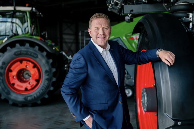 Christoph Gröblinghoff (Chairman of the Fendt Management Board) leaningn a Fendt tractor tire, another Fendtactor in the background